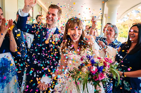 Confetti Throw, couple laughing as they walk through huge amounts of colourful confetti