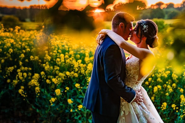 Sunset portrait, yellow flowers in background, couple kissing, captured at Bury Court, Hampshire