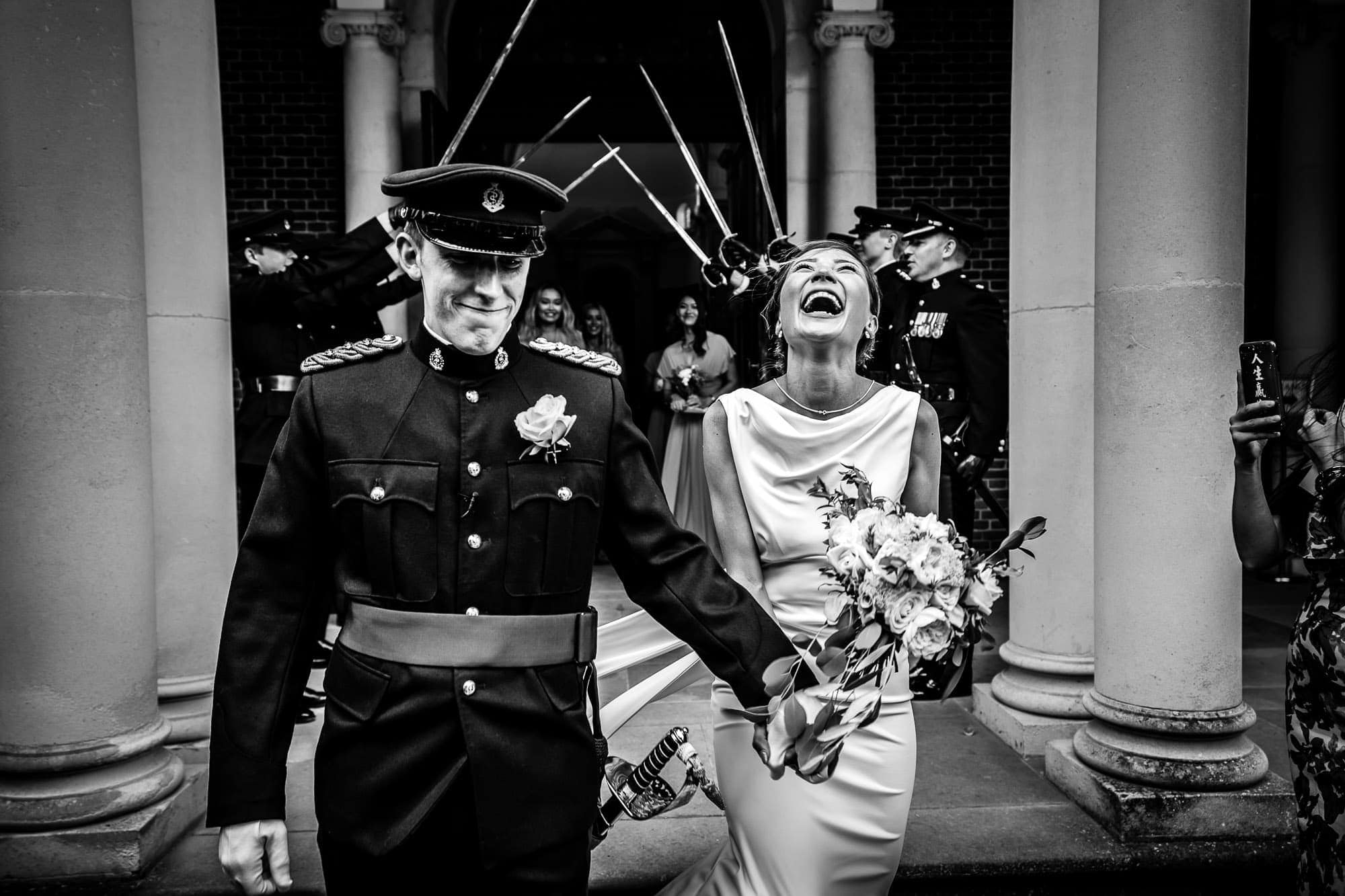 Wedding Photo of bride and groom leaving the church, groom is in military uniform, sword arch behind them. Hampshire Wedding Photography by Tansley Photography
